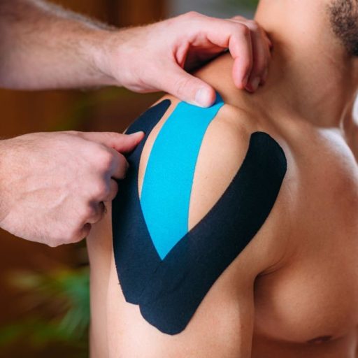 Therapist Taping Man’s Injured Shoulder with Elastic Therapeutic Kinesiology Tape