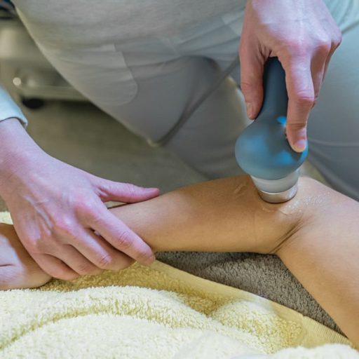 Female physical therapist using ultrasound probe on woman's arm, close up, part of the body